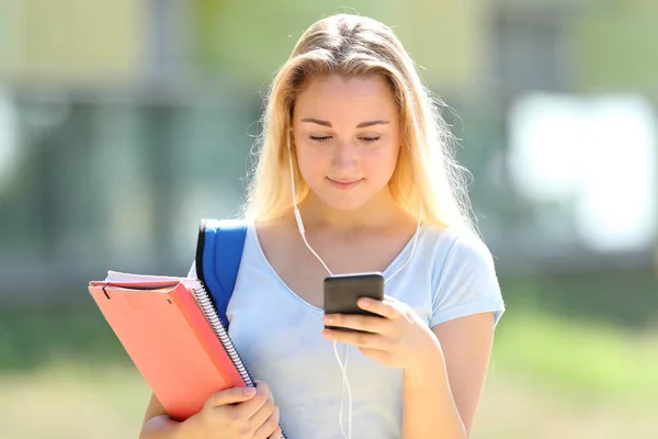 Estudante sério menina ouvindo música verifica telefone — Fotografia de Stock