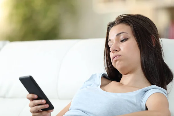 Unatkozó lány otthon nézi a mobilját. — Stock Fotó