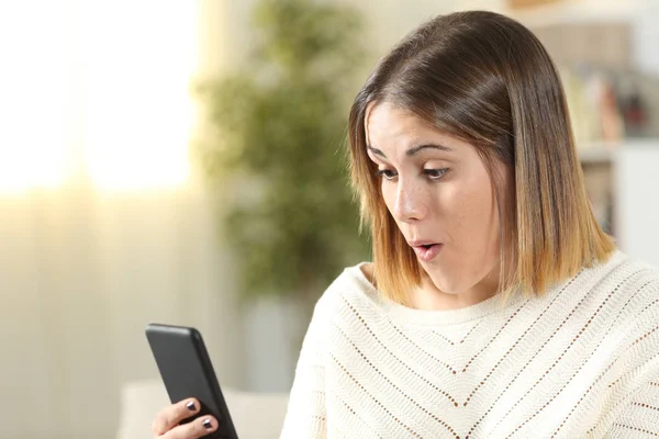 Chica sorprendida sosteniendo el teléfono inteligente en casa —  Fotos de Stock