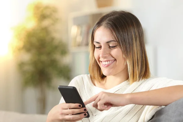 Menina feliz usa telefone inteligente em casa — Fotografia de Stock