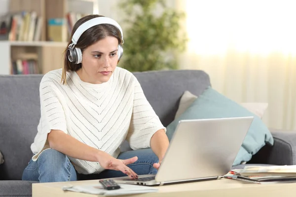 Serious female e-learning using headphones and laptop — 스톡 사진