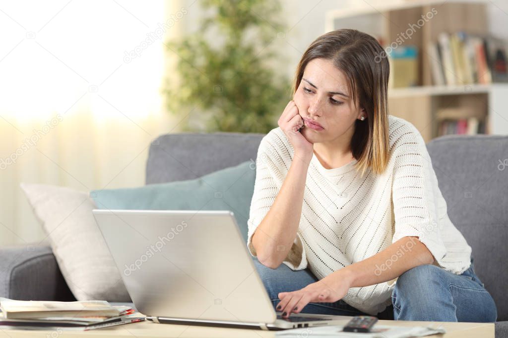 Bored woman checking laptop online content at home