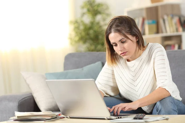 Серйозна жінка перевіряє онлайн-контент ноутбука вдома — стокове фото
