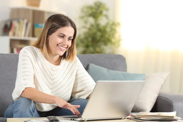 Счастливая женщина проверяет ноутбук онлайн контент дома — стоковое фото