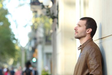 Düşünceli yetişkin adam caddeye bakıyor.
