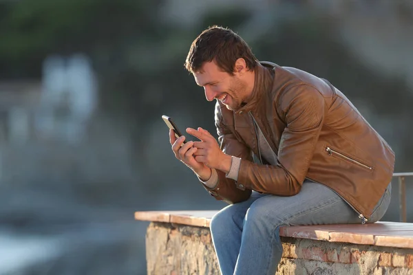 Счастливый взрослый мужчина пользуется телефоном в прибрежном городке — стоковое фото