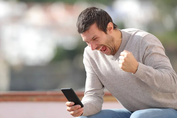 Heyecanlı adam akıllı telefondan iyi haberleri kontrol ediyor. — Stok fotoğraf