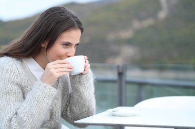 Lokanta terasında sıcak kahve içen mutlu kız.