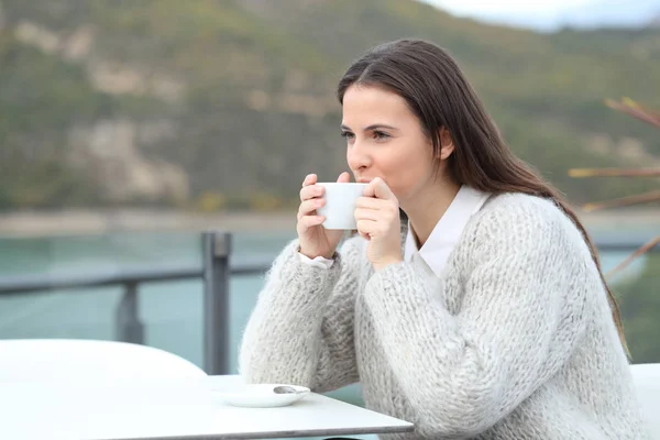 Glad flicka dricker kaffe tittar bort på en terrass — Stockfoto