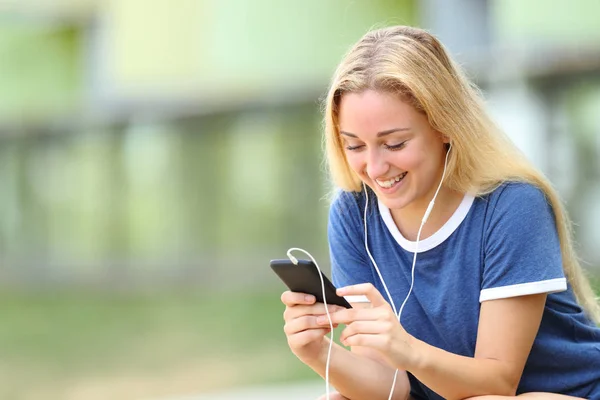 Menina adolescente feliz ouvindo música verifica telefone — Fotografia de Stock