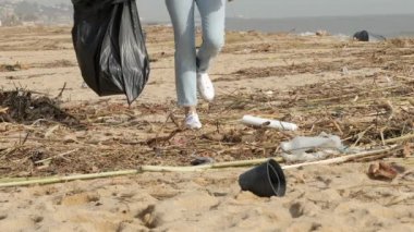 Gönüllü bir bacağın kapanması kirli bir plajı temizliyor ve fırtınadan sonra çöp topluyor.