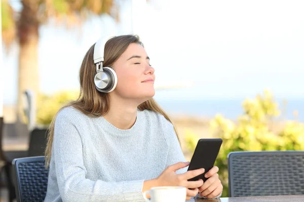 Розслаблена дівчина слухає музику з навушниками та телефоном — стокове фото