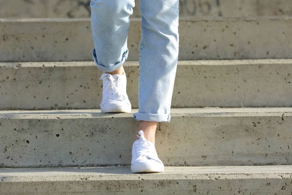 Woman legs wearing sneakers walking down stairs — Stock Photo, Image