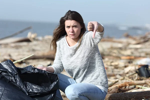 Angry volunteer cleaning a beach with thumbs down — 스톡 사진