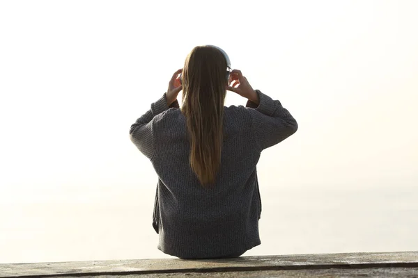 Rückansicht des Mädchens, das Kopfhörer im Freien aufsetzt — Stockfoto