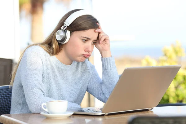 Menina frustrada verificando laptop em um terraço de café — Fotografia de Stock