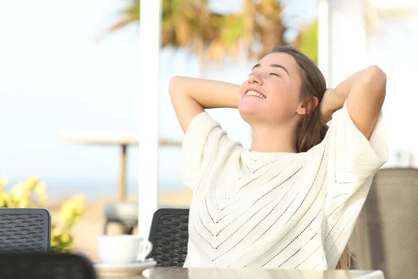 Menina feliz relaxante sentado em um terraço na praia — Fotografia de Stock