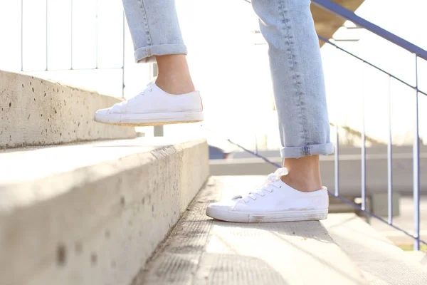 Profile of woman legs wearing sneakers walking up stairs — Stock Photo, Image