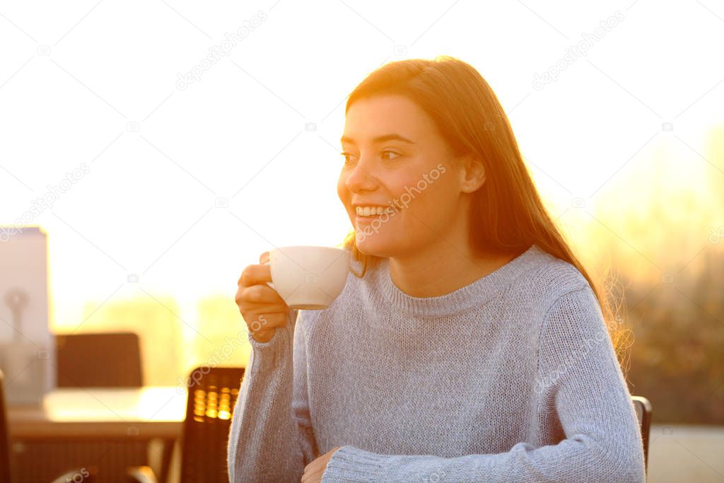 Happy girl holding coffee cup looking away in a bar terrace