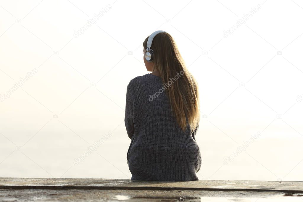Lonely woman listening to music looking at horizon