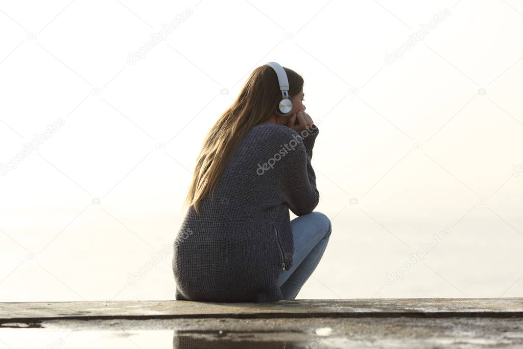 Lonely girl listening to music alone outdoors