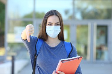 Student wearing a mask gesturing thumb down