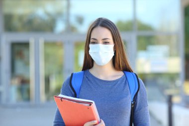 Student wearing a mask walking in a campus