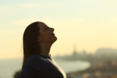 Woman silhouette breathing deeply fresh air at sunset