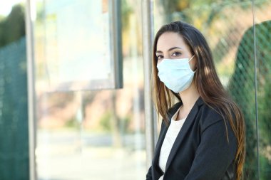 Woman wearing a mask to prevent contagion in a bus stop