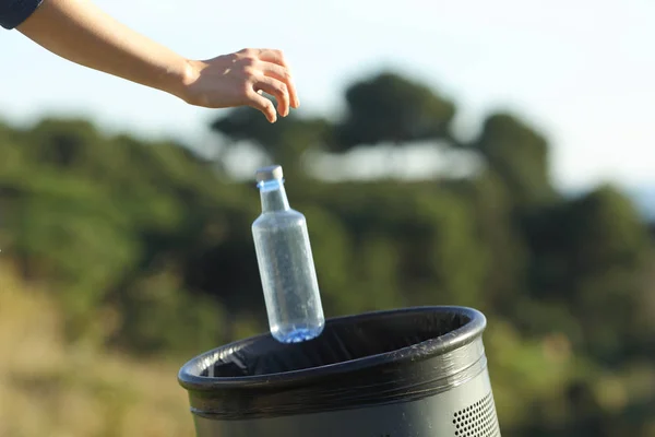 Nahaufnahme einer Frau, die eine Flasche in den Mülleimer wirft — Stockfoto