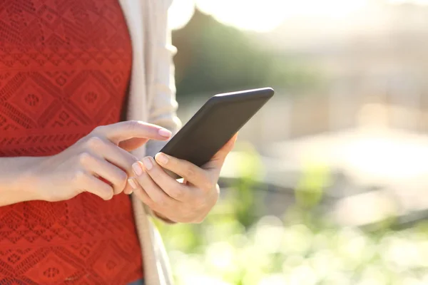 Close-up van de vrouw handen met behulp van mobiele telefoon in een park — Stockfoto