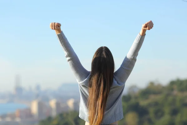 Excited woman raising arms looking at city background — ストック写真