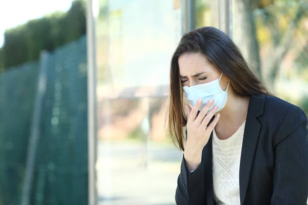 Infected woman wearing a mask coughing in a bus stop — Stok fotoğraf