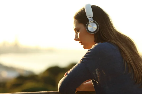 Сумна стомлена жінка слухає музику на заході сонця — стокове фото