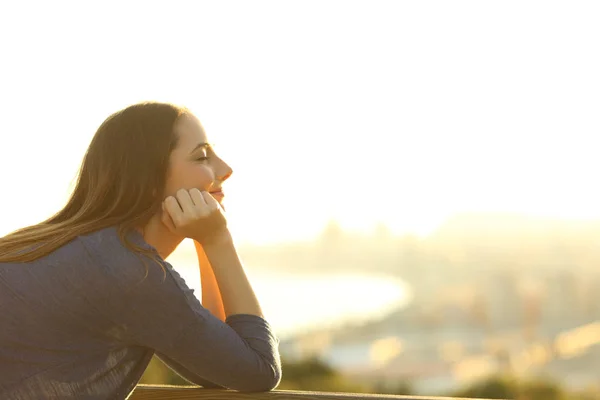 Mulher com os olhos fechados relaxante ao pôr do sol — Fotografia de Stock