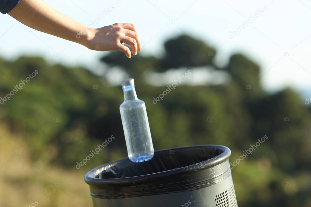 Close up of a woman hand throwing a bottle into bin