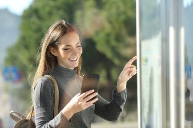 İyi yolculuklar akıllı telefonları ve otobüs durağında bekleyen programları kontrol eder.