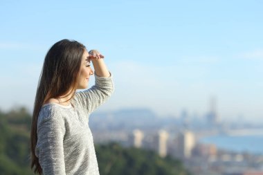 Yandan bakan bir kadının portresi güneşten korunmak için elleriyle yüzünü çeviriyor.