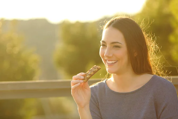 Happy Woman Eating Cereal Bar Sitting Bench Sunset Park — Stock Photo, Image