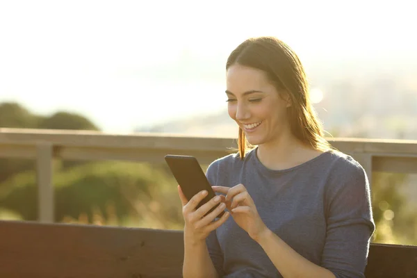 Щаслива Жінка Використовуючи Мобільний Телефон Сидить Лавці Заході Сонця Парку — стокове фото