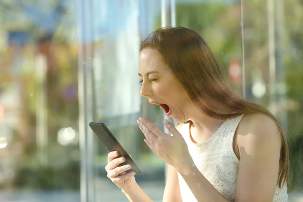 Zmęczona Kobieta Ziewanie Sprawdzanie Telefonu Komórkowego Siedzi Przystanku Autobusowym Czeka — Zdjęcie stockowe