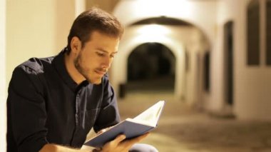 Geceleri sokakta tek başına kitap okuyan ciddi bir adam.
