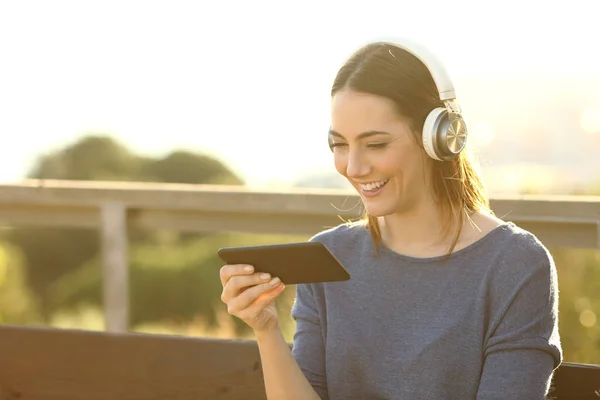 Mujer Feliz Viendo Videos Con Auriculares Teléfono Inteligente Parque Atardecer —  Fotos de Stock