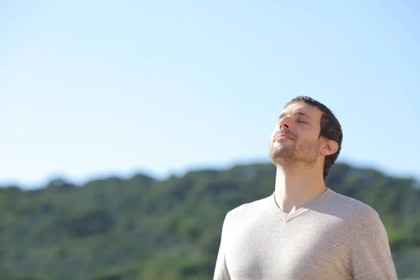 轻松自在的男人在山边呼吸新鲜空气 背景是蓝天 — 图库照片