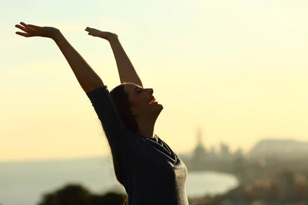 日没時に腕を上げる興奮した女性のサイドビューポートレート — ストック写真