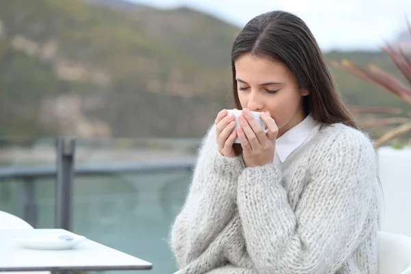 女孩坐在山上湖中的一个咖啡馆平台上 闻着咖啡的味道 — 图库照片