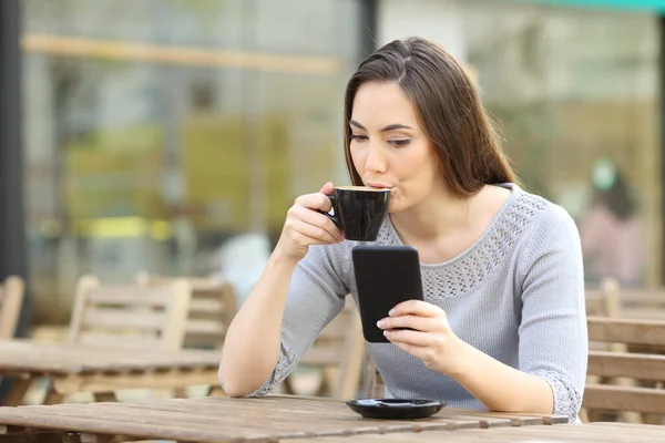 Молодая Женщина Пьет Чашку Кофе Проверяя Свой Смартфон Террасе Кафе — стоковое фото