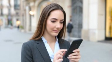 Serious executive walking using smart phone in the street