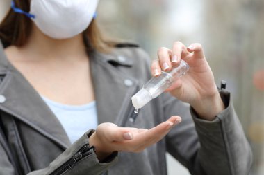 Koruyucu maskeli, elleri sterilize eden ve sokaklarda salgın olmasını önleyen bir kadına yaklaş.
