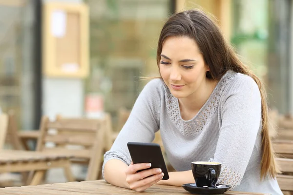 真剣な若いです女性チェック彼女のスマートフォン上のカフェテラス — ストック写真